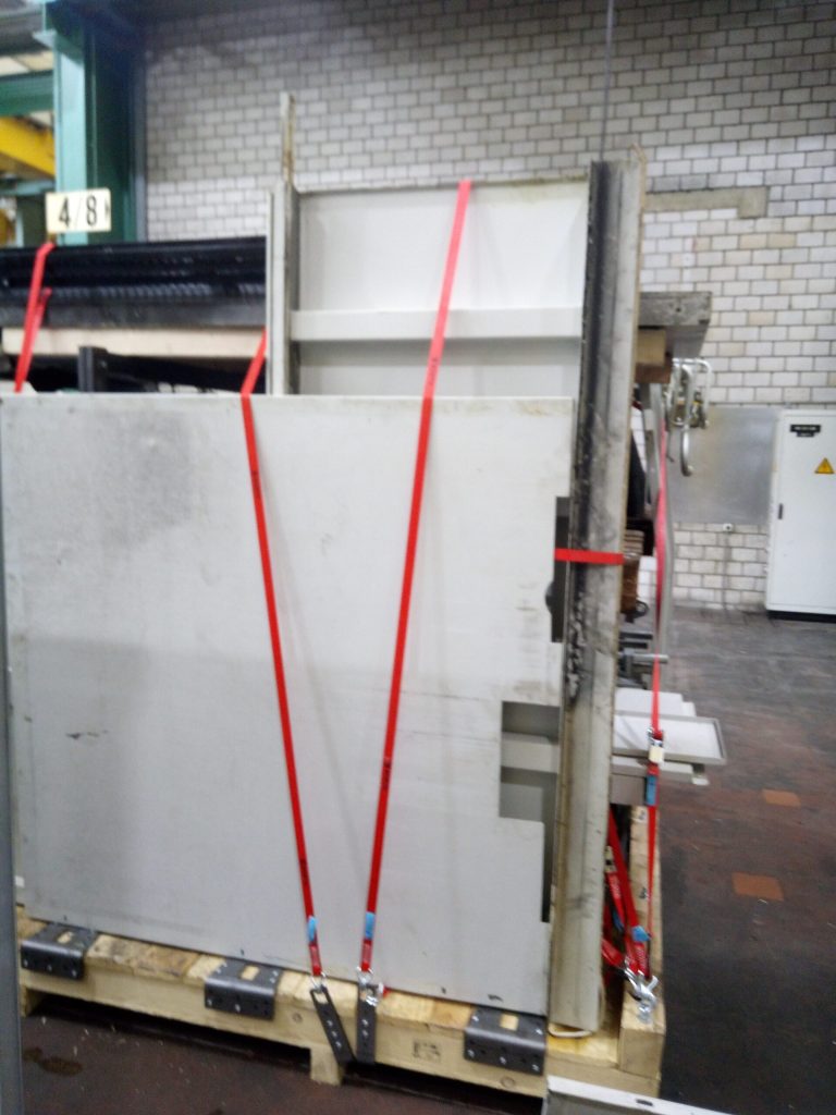 Senkrecht gelagerte große Blechteile mit flexibel geführten roten Zurrgurten auf einer Transportpalette